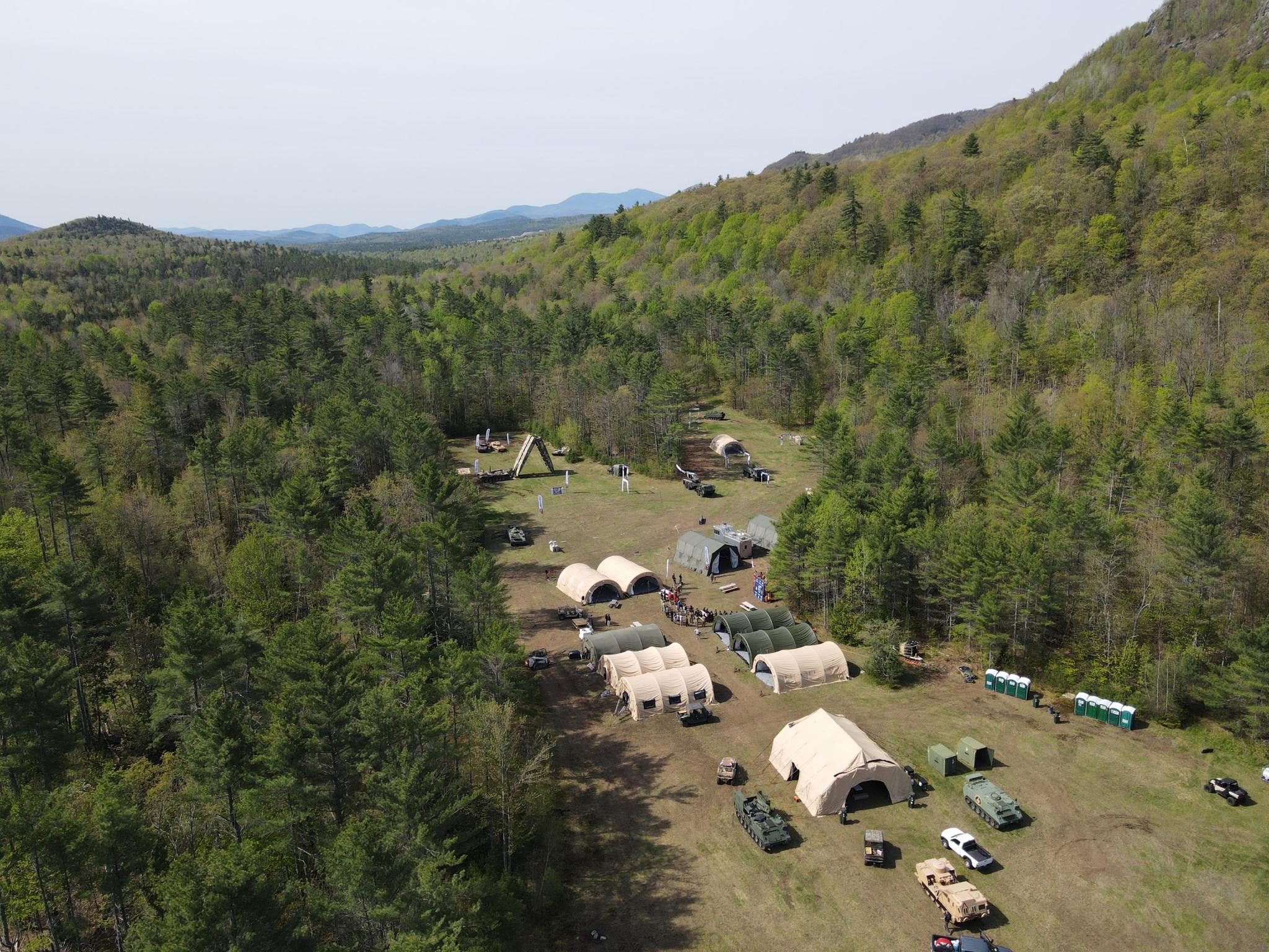 Aerial view of ADK Battlelab operations site in the Adirondacks with tents, vehicles, and staging areas